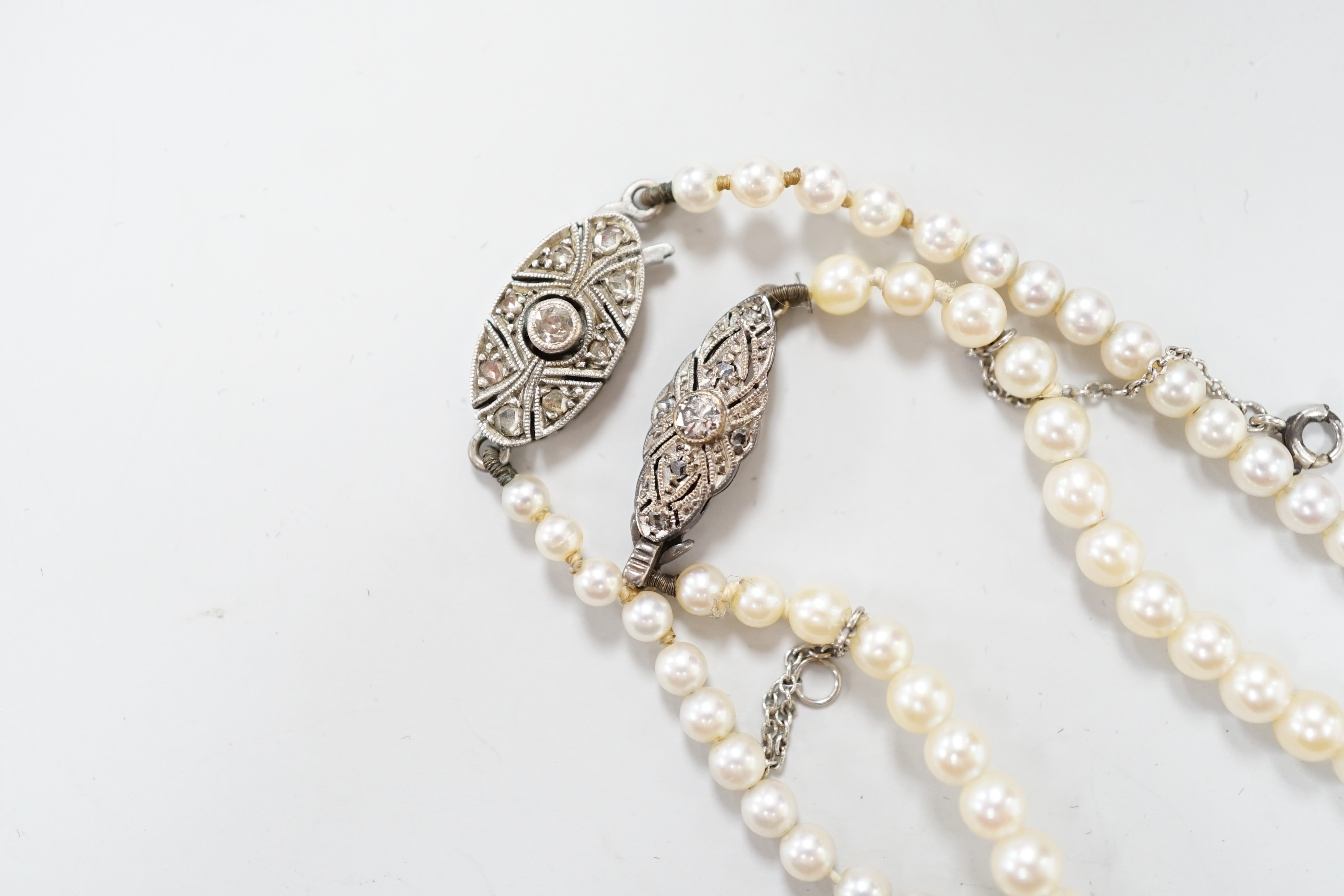 Two single strand graduated cultured pearl necklaces, both with diamond set white or yellow metal clasps, 39cm and 44cm.